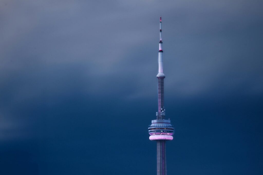 An image of the CN Tower silhouetted against a moody, cloud - filled sky. The tower is lit with a soft purple glow. Incorporated: 2025 Social Media Marketing Trends in Canada