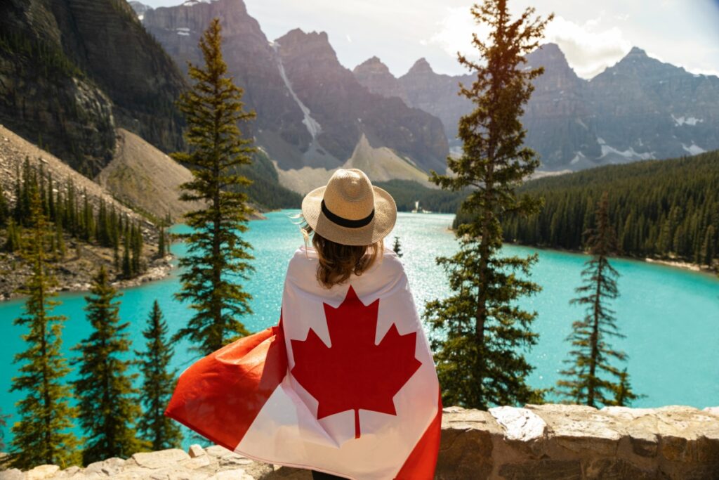 This image captures a person wrapped in a Canadian flag, gazing out at a breathtaking view of a turquoise - colored lake surrounded by majestic mountains and tall pine trees. When it comes to "Pinterest Canada How to Use Visual Marketing to Drive Sales", sharing captivating images like this can be highly effective. If you're in the tourism, outdoor gear, or souvenir business in Canada, for example, you can use this image on Pinterest. Tag it with relevant Canadian - centric hashtags such as #CanadaTravel, #CanadianNature, and #ExploreCanada. By appealing to users' desire to experience Canada's natural beauty, you can drive traffic to your products or services related to travel destinations, outdoor activities, or Canadian - themed merchandise, ultimately boosting sales.